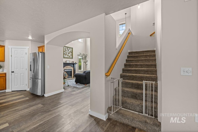 12339 W Foxhaven St, Star, ID 83669 - stairway featuring wood finished floors, a textured ceiling, arched walkways, and a fireplace