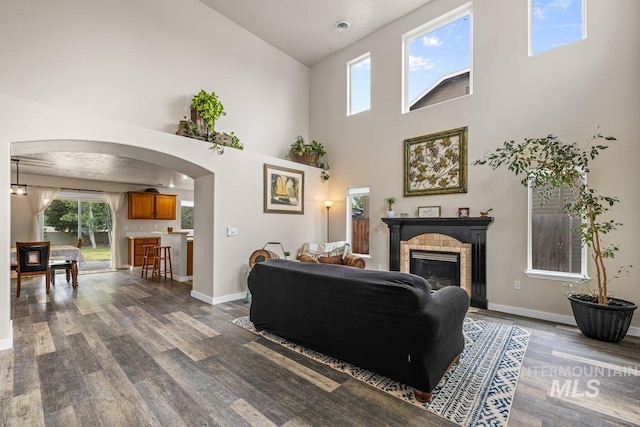 12339 W Foxhaven St, Star, ID 83669 - living room featuring dark wood-style flooring, a brick fireplace, arched walkways, and high vaulted ceiling
