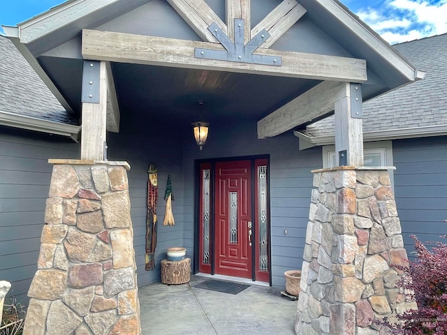 view of exterior entry with a shingled roof