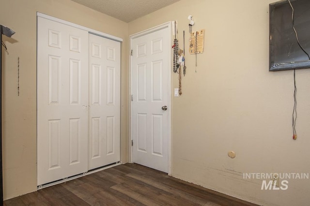 unfurnished bedroom with a closet, a textured ceiling, and dark wood finished floors