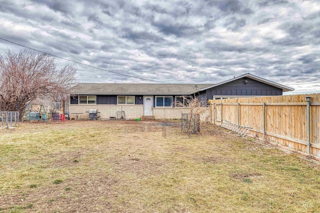 back of property with a yard, brick siding, and fence