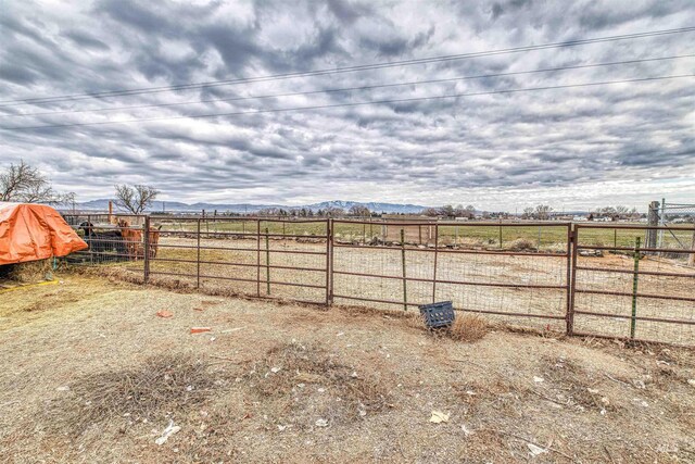 view of yard featuring a rural view, fence, and a mountain view