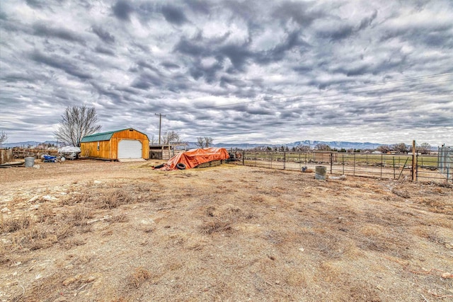view of yard with an outdoor structure, fence, a rural view, and a detached garage