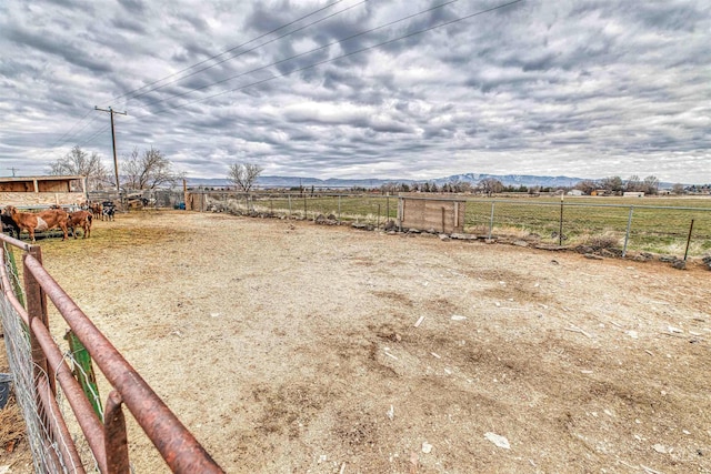 view of yard with a rural view, fence, and a mountain view