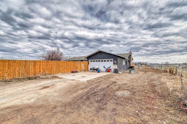 view of home's exterior with fence, an outbuilding, board and batten siding, and driveway