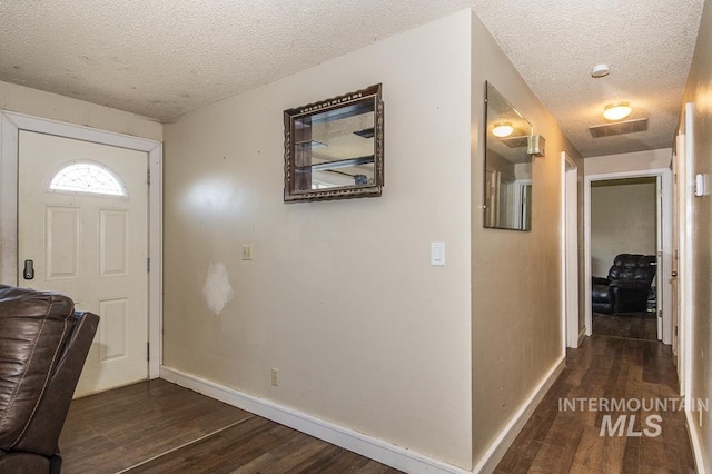 foyer with baseboards, a textured ceiling, and dark wood-type flooring