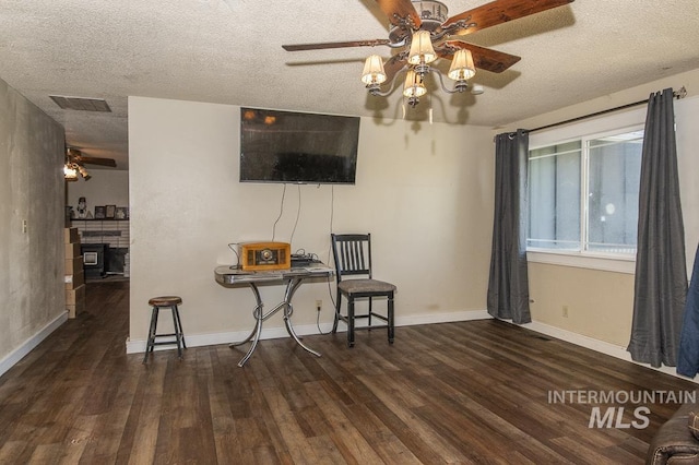 living area with a textured ceiling, ceiling fan, visible vents, and wood finished floors