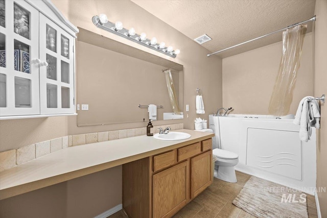 16702 Frisco Ave, Caldwell, ID 83607 - full bath featuring a tub to relax in, a textured ceiling, toilet, vanity, and tile patterned flooring