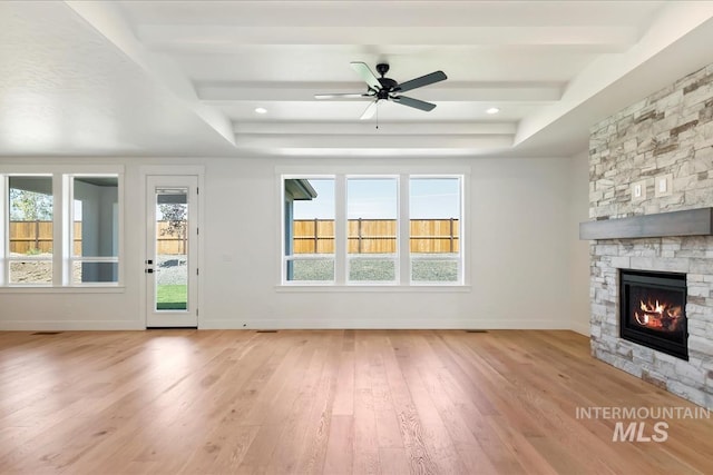 unfurnished living room featuring a healthy amount of sunlight, light hardwood / wood-style floors, a fireplace, and ceiling fan