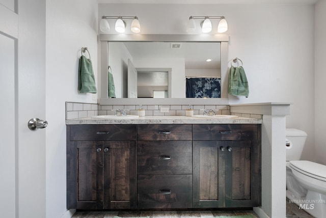 2026 Kelly Dr, Payette, ID 83661 - bathroom with double vanity, toilet, tasteful backsplash, and baseboards