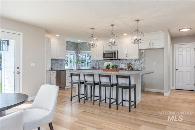 1499 E Sicily St, Meridian, ID 83642 - kitchen with stainless steel appliances, a chandelier, decorative backsplash, a breakfast bar, and white cabinetry