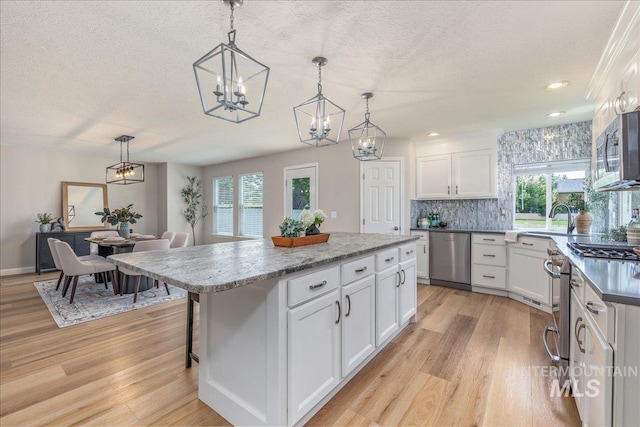 1499 E Sicily St, Meridian, ID 83642 - kitchen with appliances with stainless steel finishes, a chandelier, a textured ceiling, light wood-style floors, and white cabinets