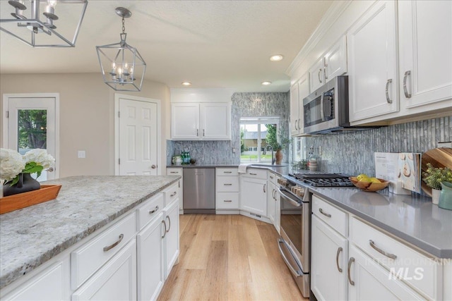 1499 E Sicily St, Meridian, ID 83642 - kitchen featuring appliances with stainless steel finishes, a chandelier, light wood-type flooring, decorative backsplash, and white cabinetry