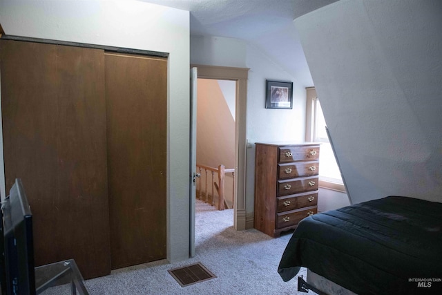 bedroom with a closet, lofted ceiling, and light colored carpet