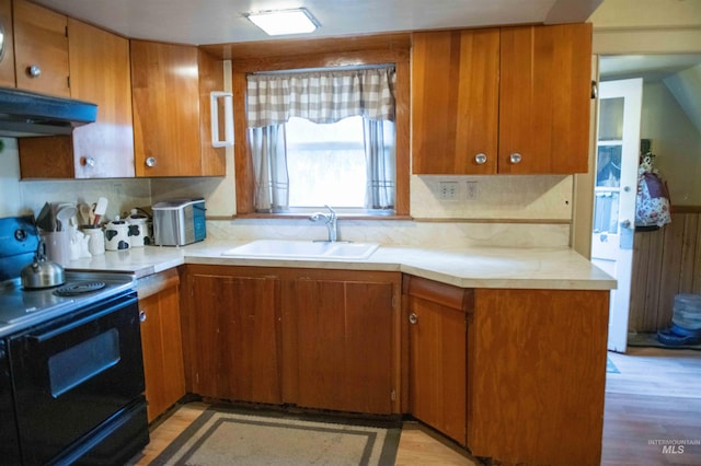 kitchen featuring black electric range, light hardwood / wood-style flooring, decorative backsplash, and sink