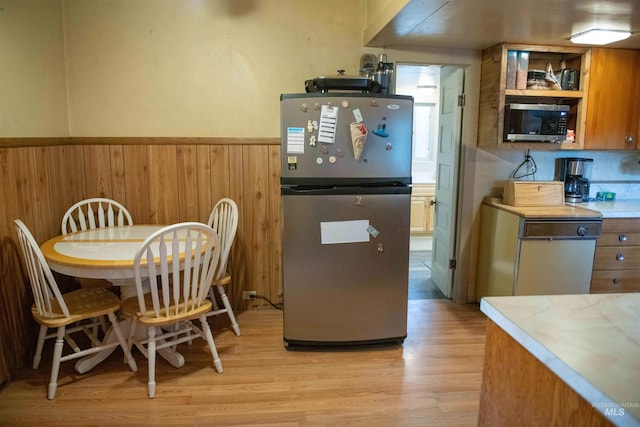 kitchen featuring wood walls, stainless steel appliances, and light wood-type flooring