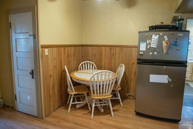 dining room with light hardwood / wood-style floors and wooden walls