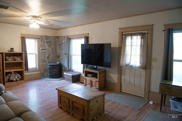 living room with light hardwood / wood-style flooring, a wood stove, and plenty of natural light