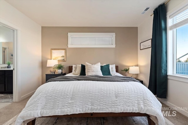 bedroom featuring light carpet and ensuite bath