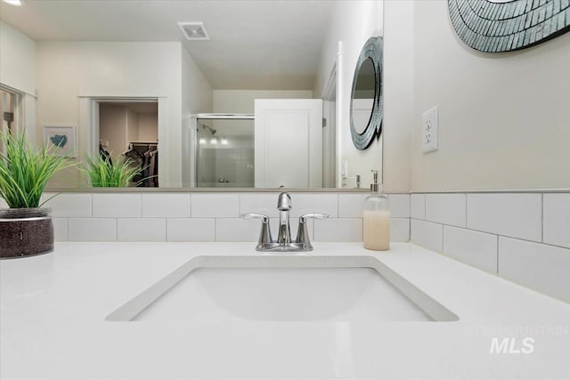 room details featuring vanity, decorative backsplash, and a shower with shower door