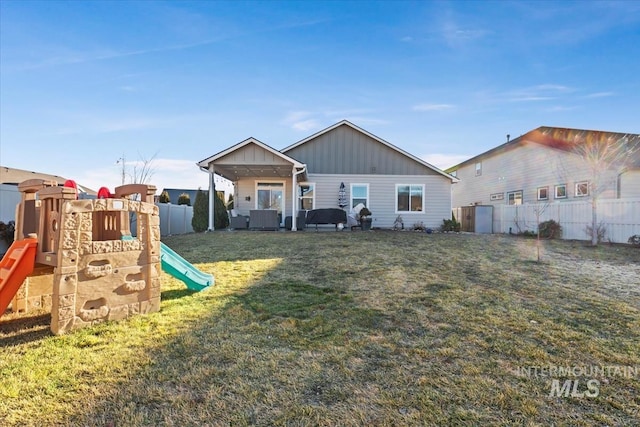 rear view of house featuring a yard, a playground, and central air condition unit