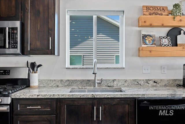 kitchen featuring appliances with stainless steel finishes, dark brown cabinetry, sink, and light stone counters