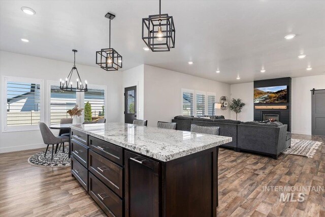 kitchen with a kitchen island, dark brown cabinets, decorative light fixtures, hardwood / wood-style floors, and a notable chandelier