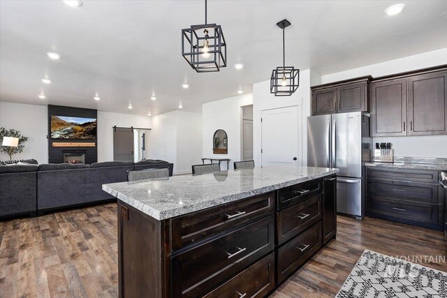 kitchen with hanging light fixtures, stainless steel fridge, dark hardwood / wood-style floors, and a kitchen island