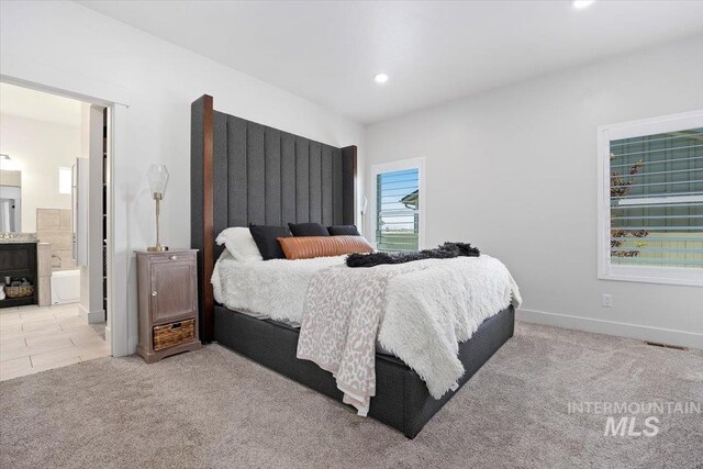 bedroom with ensuite bath and light colored carpet