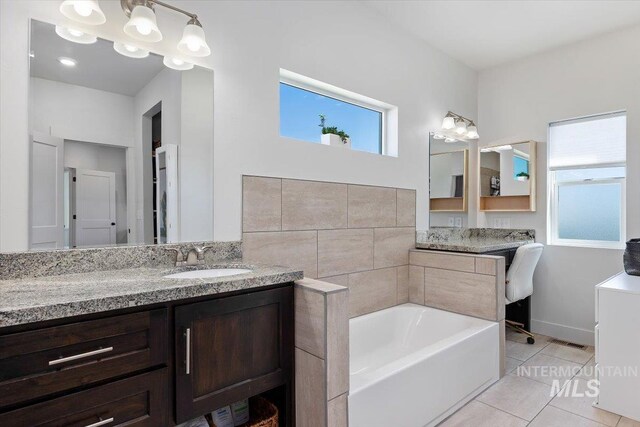 bathroom featuring vanity, a washtub, and tile patterned floors