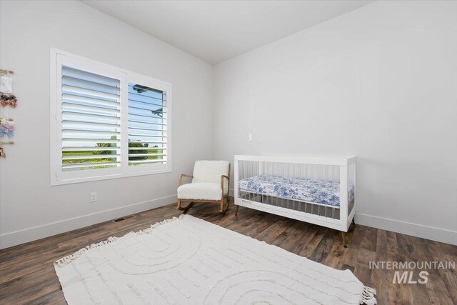 bedroom featuring a crib and dark hardwood / wood-style flooring