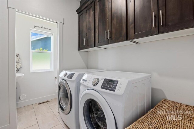 washroom with washer and clothes dryer, light tile patterned flooring, and cabinets