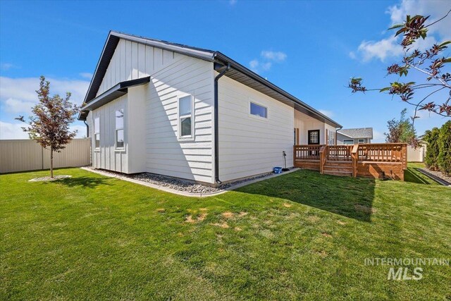 rear view of house featuring a lawn and a deck