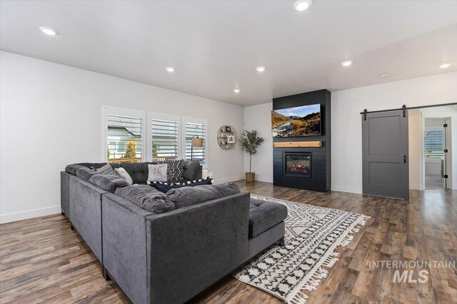 living room with a fireplace, dark wood-type flooring, and a barn door