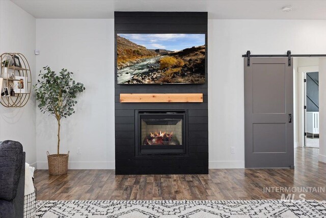 interior details with wood-type flooring, a fireplace, and a barn door