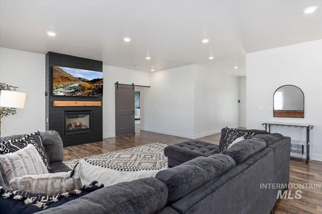 living room with a fireplace, dark hardwood / wood-style floors, and a barn door