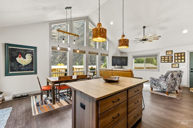 kitchen with pendant lighting, ceiling fan, high vaulted ceiling, a center island, and dark hardwood / wood-style flooring