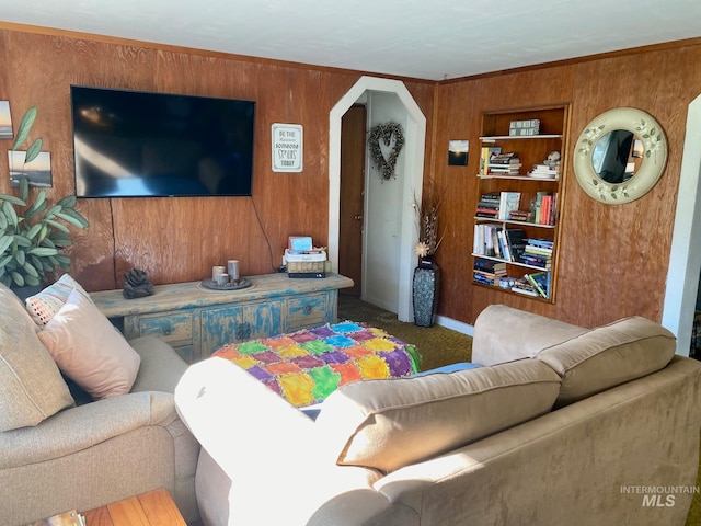 carpeted living room featuring wooden walls, built in features, and crown molding