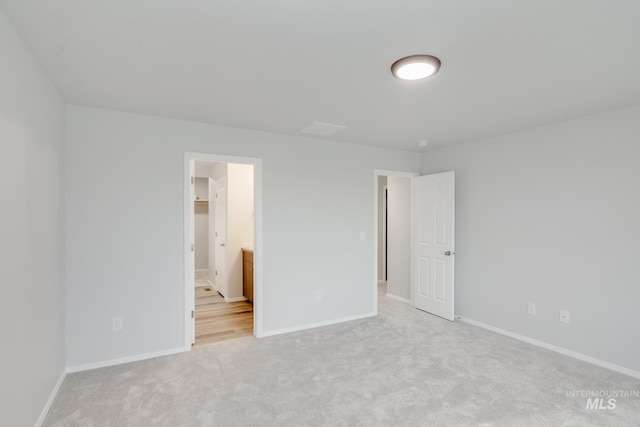 unfurnished bedroom with a spacious closet, connected bathroom, and light colored carpet