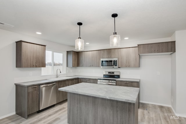 kitchen featuring sink, stainless steel appliances, hanging light fixtures, and light wood-type flooring