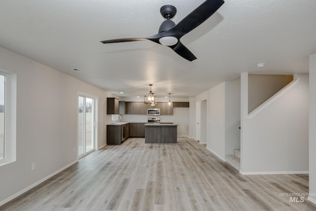 unfurnished living room featuring ceiling fan, sink, and light wood-type flooring