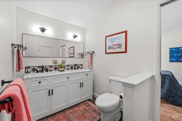 1913 W Suncrest Dr, Boise, ID 83705 - ensuite bathroom featuring double vanity, toilet, vaulted ceiling, wood finished floors, and baseboards