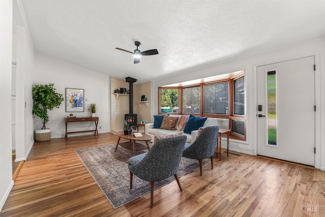 1913 W Suncrest Dr, Boise, ID 83705 - living room featuring a wood stove, wood finished floors, ceiling fan, lofted ceiling, and a textured ceiling