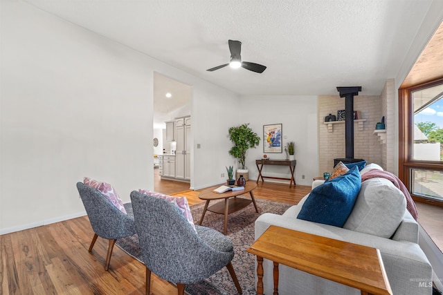 1913 W Suncrest Dr, Boise, ID 83705 - living area featuring a wood stove, ceiling fan, light wood-type flooring, baseboards, and a textured ceiling