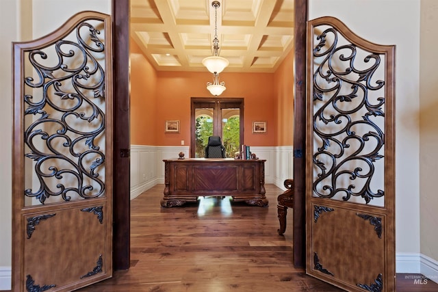 foyer with coffered ceiling, wood finished floors, beamed ceiling, a wainscoted wall, and crown molding