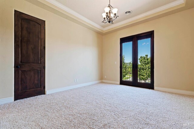 carpeted empty room with a chandelier, a tray ceiling, ornamental molding, and baseboards