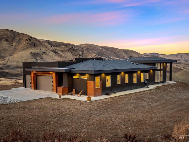 view of front of house featuring concrete driveway, roof with shingles, an attached garage, and a mountain view