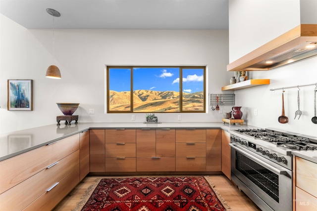 kitchen featuring light wood-style floors, hanging light fixtures, wall chimney range hood, high end stainless steel range, and modern cabinets