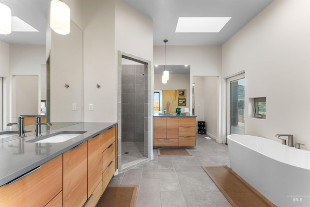 full bathroom featuring a skylight, a stall shower, a freestanding bath, and vanity