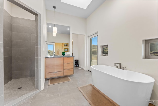 full bath with a skylight, tile patterned floors, a tile shower, vanity, and a freestanding tub